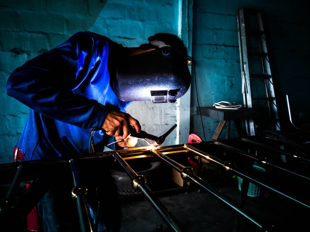 mechanic works a welding aluminium door with an electric welding machine